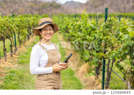 Asian winegrower working in vineyard 125094645
