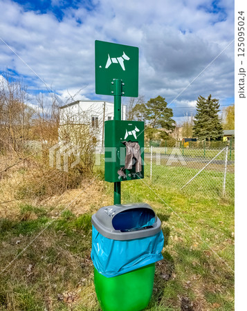 Green dog waste station with sign and trash bin on grassy roadside. High quality photo Green dog waste station with sign and trash bin on grassy roadside. High quality photo 125095024