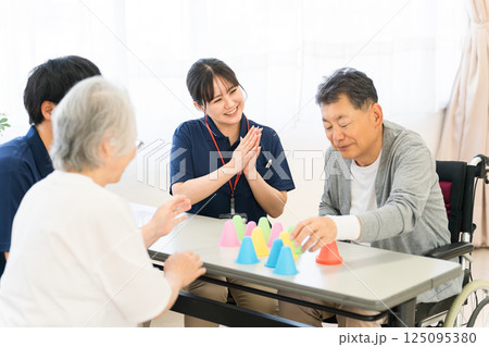 介護施設・リハビリ施設で働く作業療法士の職員とリハビリをする高齢者男女 介護施設・リハビリ施設で働く作業療法士の職員とリハビリをする高齢者男女 125095380