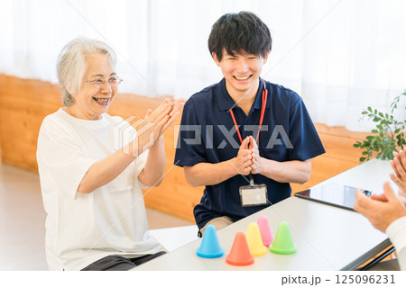リハビリ施設,介護施設で働く若いアジア人男性スタッフとシニア女性 125096231
