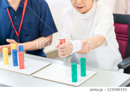 介護施設・リハビリ施設で働く作業療法士の職員とリハビリをするシニア女性 介護施設・リハビリ施設で働く作業療法士の職員とリハビリをするシニア女性 125096350