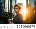 Business success - businesswoman with paper cup of coffee in the city center at skyscrapers 125096676