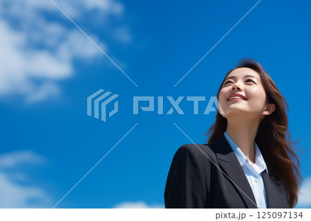 笑顔で空を見上げるスーツ姿の新入社員の若い女性 125097134