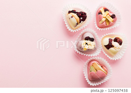 chocolate sweets in the form of a heart with fruits and nuts on a colored background. top view with space for text, holiday concept 125097438