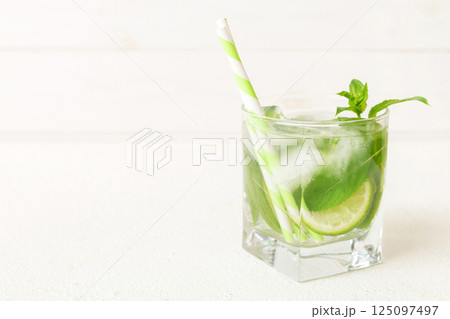 Mojito cocktail. Refreshing mojito cocktail with lime, lemon and mint in a tall glass with a stick 125097497