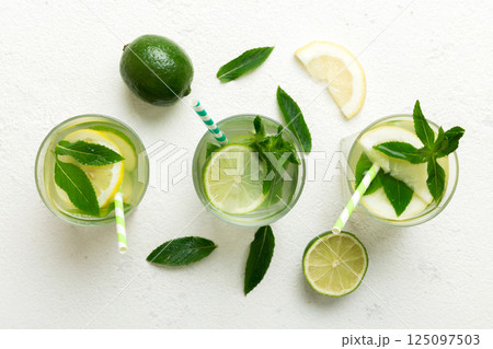 Caipirinha, Mojito cocktail, vodka or soda drink with lime, mint and straw on table background. Refreshing beverage with mint and lime in glass top view flat lay Caipirinha, Mojito cocktail, vodka or soda drink with lime, mint and straw on table background. Refreshing beverage with mint and lime in glass top view flat lay 125097503