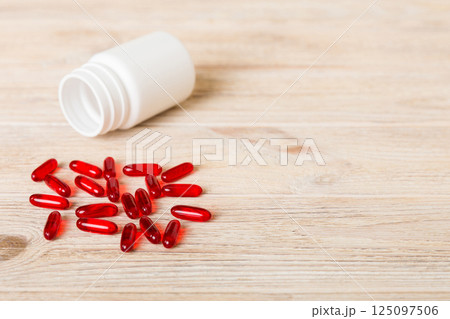 Red pills spilled around a pill bottle. Medicines and prescription pills flat lay background. Red medical capsules Red pills spilled around a pill bottle. Medicines and prescription pills flat lay background. Red medical capsules 125097506