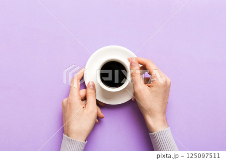 Minimalistic style woman hand holding a cup of coffee on Colored background. Flat lay, top view cappuccino cup. Empty place for text, copy space. Coffee addiction. Top view, flat lay 125097511