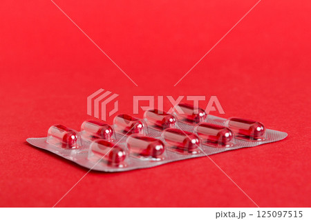 Blister package with Vitamin a on color background. Medicine pills on a light background. Medicines and prescription pills flat lay background. red medical tablets in blister Blister package with Vitamin a on color background. Medicine pills on a light background. Medicines and prescription pills flat lay background. red medical tablets in blister 125097515
