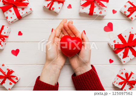 Close up on female hands holding a heart in a colored background for valentine day, birthday, mother's day. Flat lay top view Close up on female hands holding a heart in a colored background for valentine day, birthday, mother's day. Flat lay top view 125097562