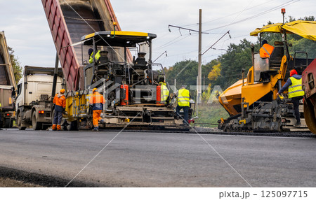 Two Asphalt Paver Machine laying fresh asphalt on road construction site. Two Asphalt Paver Machine laying fresh asphalt on road construction site. 125097715