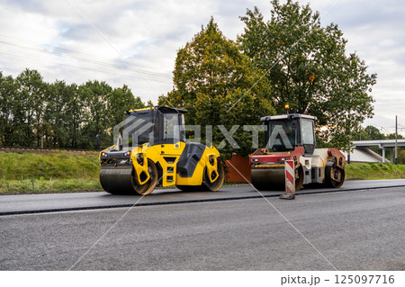 Two Heavy Asphalt Road Roller that press new hot asphalt on the roadway on a road construction site Two Heavy Asphalt Road Roller that press new hot asphalt on the roadway on a road construction site 125097716