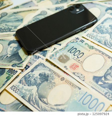 たくさんの千円札とスマホ 125097924