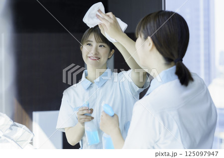 オフィスビルの洗面所の鏡を拭く若い女性清掃員　撮影協力：学校法人電波学園 東京電子専門学校 125097947
