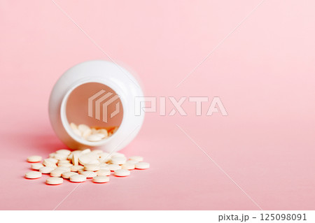 Medicine bottle and white pills spilled on a light background. Medicines and prescription pills flat lay background. White medical pills and tablets spilling out of a drug bottle Medicine bottle and white pills spilled on a light background. Medicines and prescription pills flat lay background. White medical pills and tablets spilling out of a drug bottle 125098091