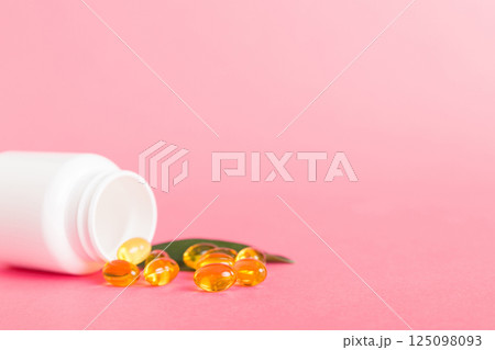 Soft gels pills with Omega-3 oil spilling out of pill bottle close-up. Gel capsules bottle white surface. Omega 3, multivitamins, Calcium, antibiotics. Health. Immunity 125098093