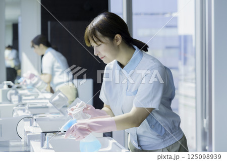 オフィスビルの洗面所の洗面台を拭く若い女性清掃員　撮影協力：学校法人電波学園 東京電子専門学校 125098939