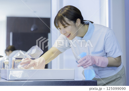オフィスビルの洗面所の洗面台を拭く若い女性清掃員　撮影協力：学校法人電波学園 東京電子専門学校 125099090