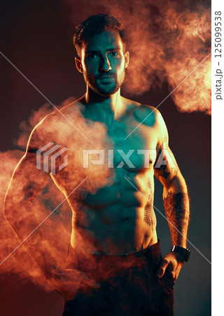 Fitness, body and man in a studio with smoke or mist after an intense workout or bodybuilding training. Sports, health and portrait of a bodybuilder or athlete with muscle isolated by dark background Fitness, body and man in a studio with smoke or mist after an intense workout or bodybuilding training. Sports, health and portrait of a bodybuilder or athlete with muscle isolated by dark background 125099538