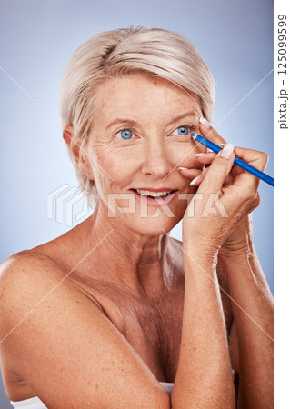 Beauty, makeup and eyeliner with a senior woman in studio on a gray background to apply cosmetics to her face. Eyes, product and luxury with a mature female applying a cosmetic with an eye pencil 125099599