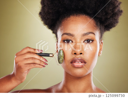 Skincare, face roller and black woman in studio portrait with facial massage for natural beauty, cosmetics and facial wellness product. African beauty model with stone rose quartz in dermatology care Skincare, face roller and black woman in studio portrait with facial massage for natural beauty, cosmetics and facial wellness product. African beauty model with stone rose quartz in dermatology care 125099730