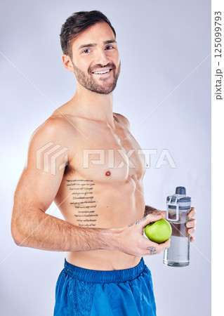Water bottle, apple and healthy man in studio portrait for diet, clean body and fitness marketing or advertising. Sports, strong and gym model with muscle wellness, healthy food and fruit nutrition 125099793