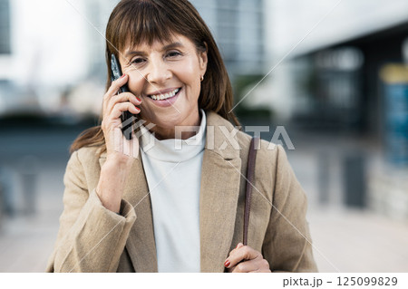 Senior woman, business and phone call on walk in city for communication with smile outdoor. Corporate conversation, happy entrepreneur or networking in metro, urban or street with talk on smartphone Senior woman, business and phone call on walk in city for communication with smile outdoor. Corporate conversation, happy entrepreneur or networking in metro, urban or street with talk on smartphone 125099829