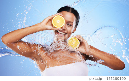 Water splash, lemon and skincare with beauty, product and advertising body wellness, cleaning and hygiene in blue studio background. Health, clean or skin with an young female model and natural fruit 125100190