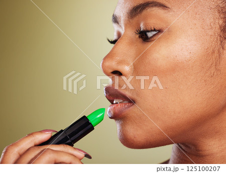Woman, mouth and lipstick for makeup and cosmetic beauty aesthetic on a green studio background. Black woman, green lipstick glamour for lipbalm, skincare and pout treatment for plump lips 125100207