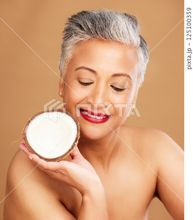 Beauty, coconut and skincare with woman in natural cosmetic product advertising against studio background. Healthy skin, fresh and clean with organic cosmetics, face and body care for antiaging. 125100359