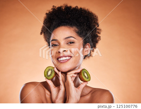 Kiwi fruit, beauty and black woman healthcare or vitamin c nutrition for skincare health. Portrait of African girl model, diet wellness or healthy cosmetics and facial care in brown background studio 125100776