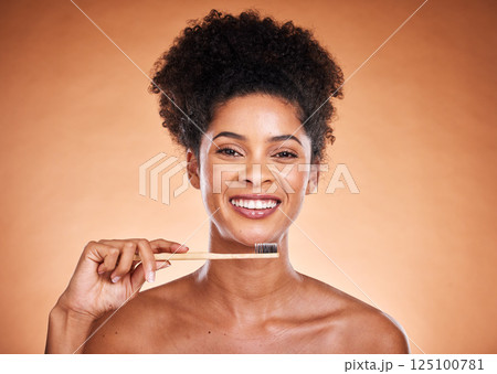 Dental care, toothbrush and hygiene with a model black woman brushing her teeth in studio on a beige background. Portrait, face and oral treatment with an attractive young female proud of her routine 125100781