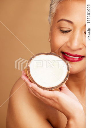 Beauty, skincare and coconut with a senior woman in studio on a brown background to promote natural antiaging care. Cosmetics, moisture and hydration with a mature female posing with a fruit half Beauty, skincare and coconut with a senior woman in studio on a brown background to promote natural antiaging care. Cosmetics, moisture and hydration with a mature female posing with a fruit half 125101096