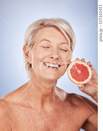 Grapefruit, skincare and senior woman with food for beauty, aging and wellness against a grey studio background. Smile, healthy and excited elderly model with a fruit with nutrition for body 125101451