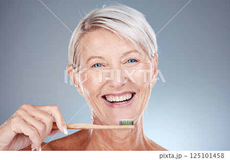 Portrait, senior woman and brushing teeth for dental hygiene, fresh breath and smile against grey studio background. Oral health, mature female and elderly lady with toothbrush and cleaning mouth. 125101458