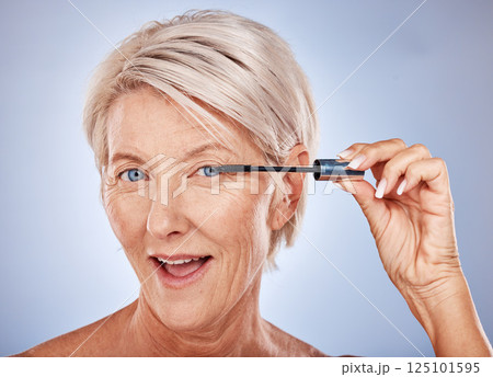 Makeup, mascara and portrait of a senior woman with a natural, cosmetic and beauty routine in a studio. Cosmetics, beautiful and elderly model with a eyelash product isolated by a gray background. 125101595