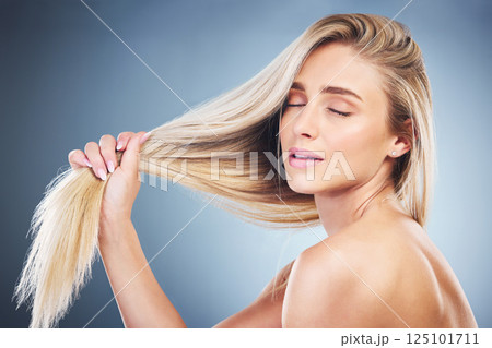 Face, beauty and hair with a model woman in studio on a blue background for haircare or wellness. Salon, hairstyle and cosmetics with an attractive young female posing to promote keratin treatment 125101711
