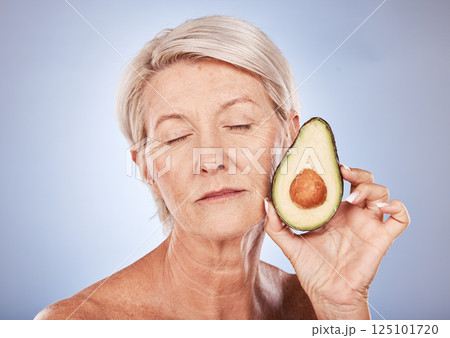 Mature, beauty and skincare with a woman and an avocado for smooth, soft skin on a grey background. Anti aging, skin care facial treatment with fresh food for senior female with avo for health 125101720