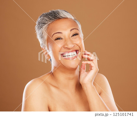 Skincare, wellness and senior woman with makeup for face with a smile and happy against a brown studio background. Beauty, portrait and elderly cosmetic model with happiness for glow in retirement 125101741