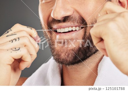 Floss, dental hygiene and man cleaning teeth, for wellness and against grey studio background. Oral health, healthy male and thin filaments string for fresh breath, remove plaque and mouth healthcare 125101788