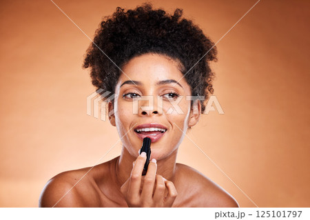Black woman, afro and face glow lipstick on studio background for morning grooming routine, self care or satisfaction. Smile, happy or beauty model with lip gloss, makeup cosmetics and color product 125101797