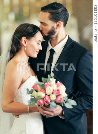 Wedding, couple and forehead kiss with love while holding a bouquet of flowers for marriage, walking down the isle and marry. Bride, groom and newlywed people happy together after a celebration event 125101808