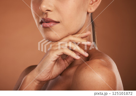 Hand, lips and woman with glowing skincare on brown studio background with healthy, wellness manicure and self care dermatology. Zoom, beauty model and mouth with lipstick cosmetics or makeup product 125101872