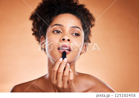 Lipstick, black woman and cosmetics for smooth, glow and skincare with confidence with brown studio background. Lips, African American female and girl with gloss, makeup and natural beauty for mouth 125102458
