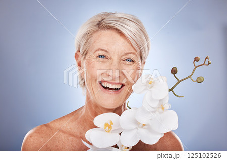 Face, beauty and flowers with a mature woman in studio on a gray background with an orchid for natural care. Portrait, cosmetics and plant with a senior female posing to promote the benefit of nature 125102526