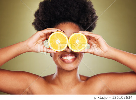 Skincare, beauty and happy woman with lemon in a studio for a natural, healthy and organic face routine. Cosmetics, citrus fruit and black model with a smile for facial treatment by green background. 125102634