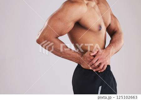 Pain, waist and man with an injury after exercise, fitness and training against a grey studio background. Healthcare, accident and person feeling their body with appendicitis and medical emergency 125102663