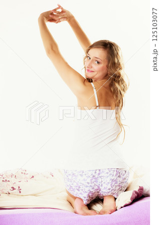 woman waking up in bed stretching her arms up woman waking up in bed stretching her arms up 125103077