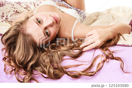 woman long curly hair relaxing on her bed at morning 125103080