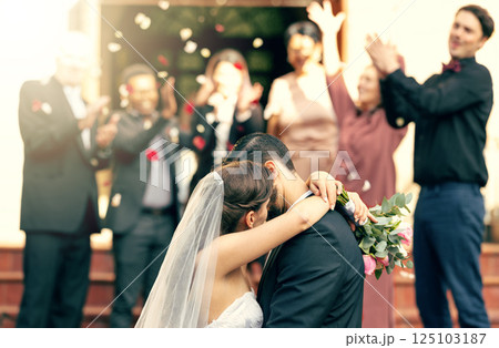Bride, groom and kiss in wedding celebration with applause from family, friends or guests at the church. Man and woman couple kissing, hugging or embracing marriage in romance for happy relationship 125103187